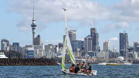 A group of people sailling with Auckland city in the background
