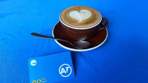 Cup of coffee and AT HOP card on blue background