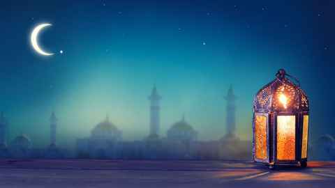 Blue background with a lantern in the foreground signifying Eid al-adha