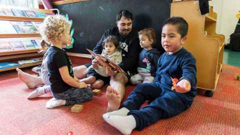 Photo of Daniel Hepi reading to children at Hineteiwaiwa 