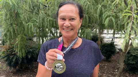 Photo of Suzanne Jackson holding up her gold medal. 