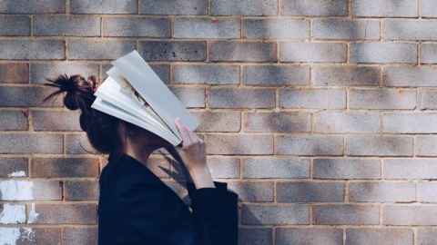 student holding book up to cover her face