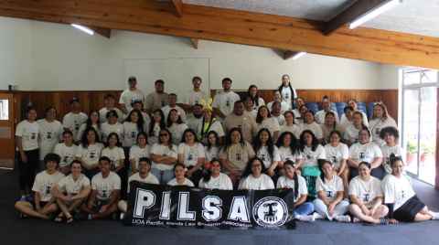 A large group of people with a banner in front that reads: 'PILSA: UoA Pacific Islands Law Students Association'.