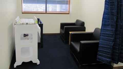 Parenting room with two comfy chairs, a cot and a changing table.