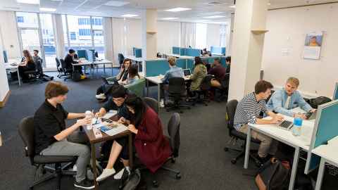 A large study space, with students working together at tables and desks.
