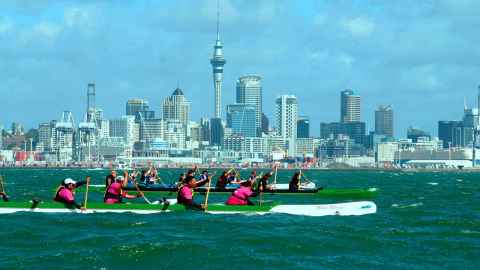 racing canoes passing Auckland city