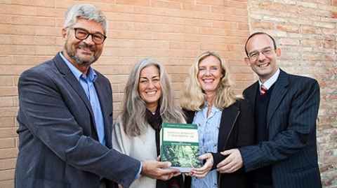 Two men and two women holding a book.