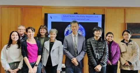 A group of people standing in front of a screen with the words "Small states, the polar regions and international law".