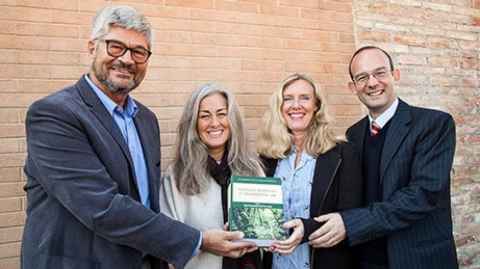 Two men and two women holding a book.