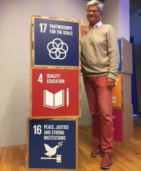 A man with boxes featuring the UN SDG goals.