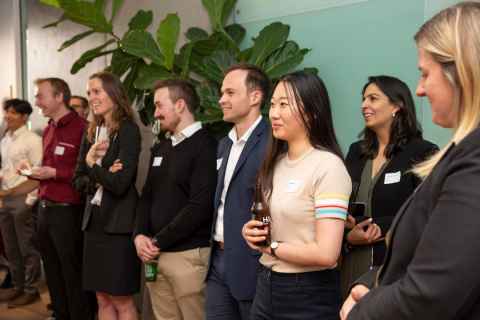 A group of smiling people standing around a room.