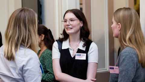 Three young women at an event, talking.