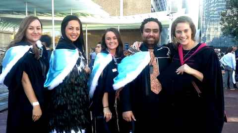 Four Māori students dressed in Law regalia for graduation.