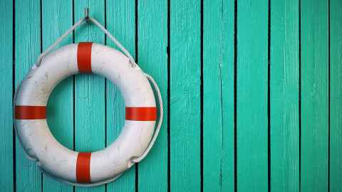 A red and white life ring hanging on blue painted wooden shed wall