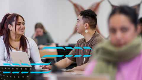 Image of two people sitting at a desk talking
