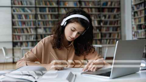 Image of girl studying at a desk with headphones on