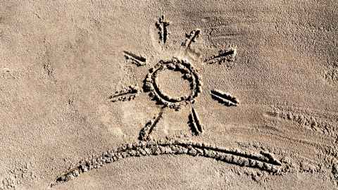 Photo of a sunshine symbol drawn in the sand.