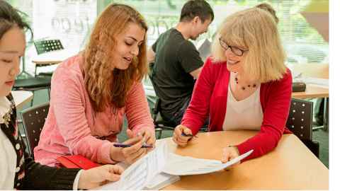 Photo of a volunteer helping a student learn English. 