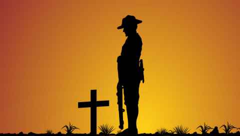 A silhouette of an ANZAC soldier standing in front of a cross marking a grave.