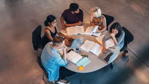 High angle image of a group of students sitting around a circular table studying together