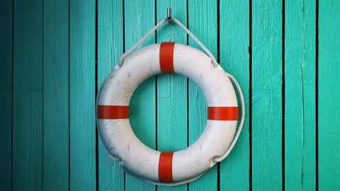 Red and white life saver ring on a green wooden background