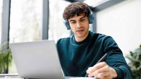 A photo of a male student studying in front of his laptop.
