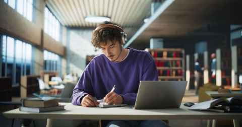 An image of a student studying at a desk in the Library in front of a laptop