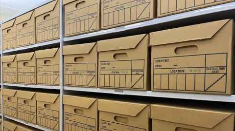 Image of filing boxes neatly stacked on a long shelf