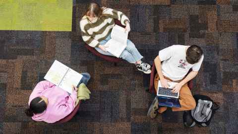 Three people reading in the library