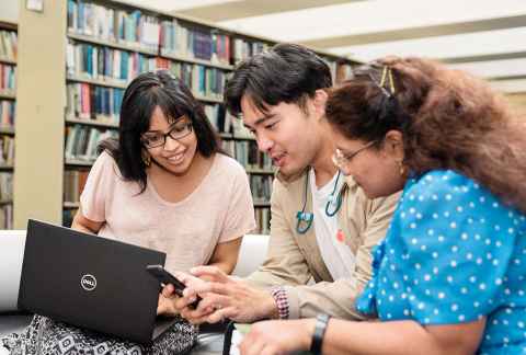 Three students using a laptop and phone