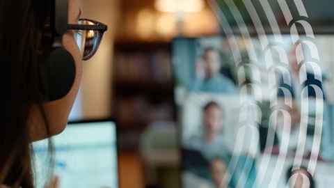 Woman with headphones looking at computer screen