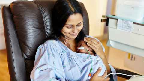 Mother cradling her newborn baby with feeding tube