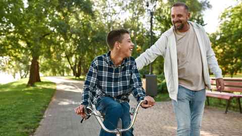 Body with cerebral palsy rides a bike with this father