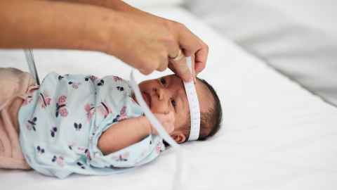 Nurse measuring the circumference of a newborn baby's head