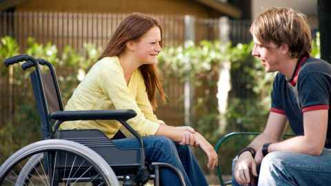 student in a wheelchair talking to another student