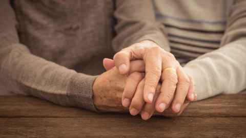 Two older people holding hands