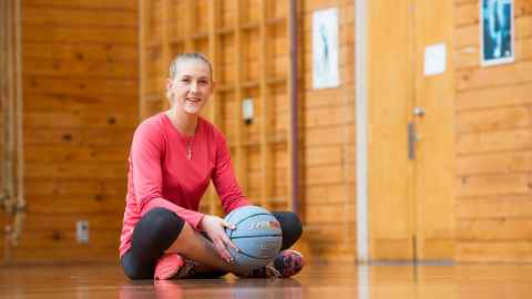 Michaela Sokolich-Beatson sitting on a gymnasium floor holding a ball