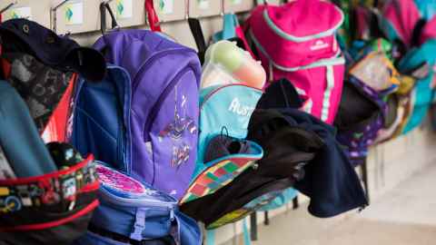 School bags hanging on a row of hooks