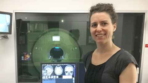 Dr Samantha Holdsworth next to a computer screen showing MRI images