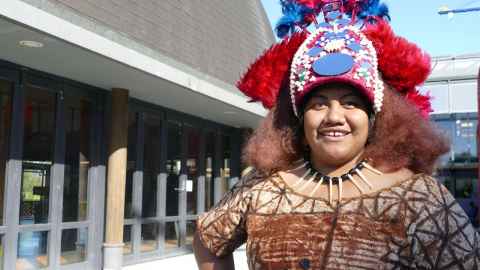 Sabrina Wright wearing traditional Samoan dress and standing outside the Fale Pasifika.