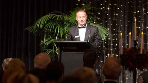 John McCall MacBain standing at a podium