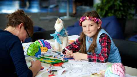 Adult and child with colouring pens and pictures and models of the brain.