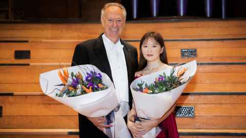 Conductor Uwe Grodd with Jisu (Jessica) Yun, both holding bouquets of flowers