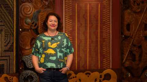 Ngarino Ellis standing next to tukutuku panels and carvings.