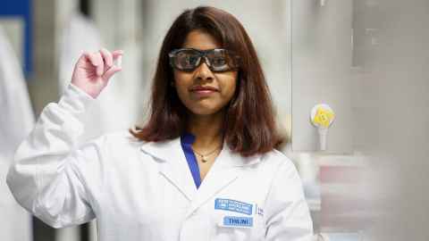 Thilini Vidanelage wearing a white lab coat and holding a capsule