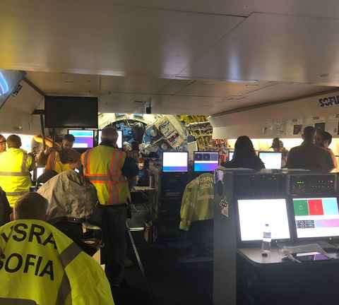 Aboad the NASA SOFIA's flight deck with the infrared telescope in the background.