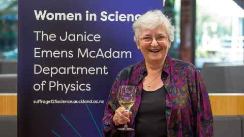 Janice Emens McAdam with the banner naming The Janice Emens McAdam Department of Physics.