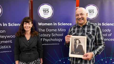 Dame Mira Szászy's son Philip (holding Dame Mira's graduation portrait) and his wife Annette with the banner naming The Dame Mira Szászy School of Psychology.