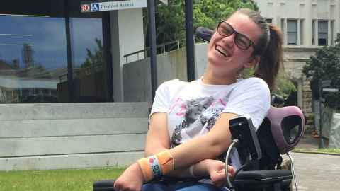 Alicia Kapa, in a wheelchair, laughing, outside Alfred Nathan House