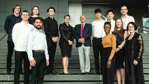 Professor Jayne Godfrey, Sir Owen Glenn, and Susan Laurenson with scholarship winners gathered on the main stairs at the Sir Owen G Glenn building